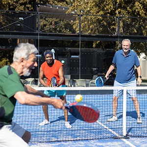 group of men playing pickle ball on an outdoor court